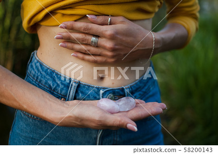 Adult woman is holding two yoni eggs for vumfit, imbuilding or meditation are made from pink quartz Adult woman is holding two yoni eggs for vumfit, imbuilding or meditation are made from pink quartz 58200143