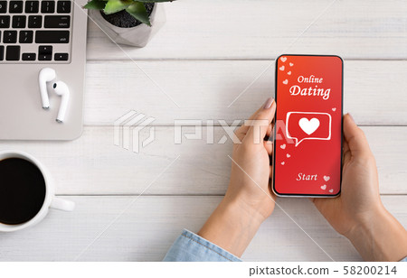 Woman downloading dating app on smartphone during coffee break 58200214