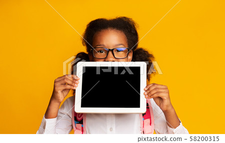 African American Schoolgirl Hiding Behind Tablet Blank Screen, Yellow Background 58200315