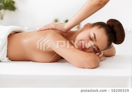 Masseur doing back massage to young woman in spa salon 58200329