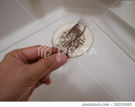 A woman's hand destined to pinch her hair with a finger in the drain A woman's hand destined to pinch her hair with a finger in the drain 58203993