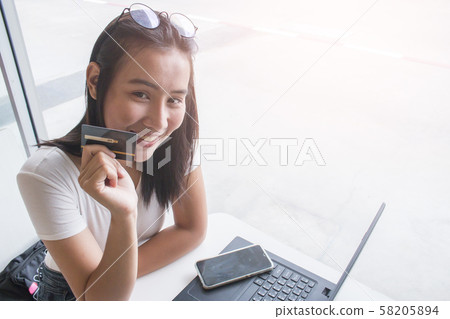 Smiling asian young female model holding up credit 58205894