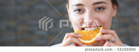 Beautiful brunette smiling woman eat sliced orange 58208990