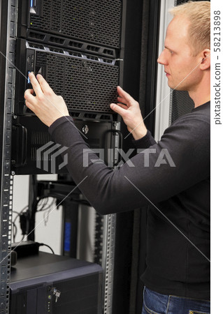 It consultant working with installation of a server in datacenter 58213898