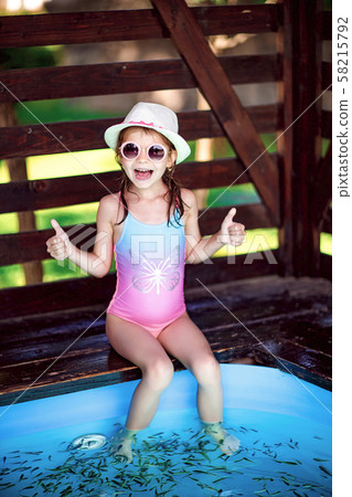 Young girl receiving massage with small fishes. Peeling with fish. Girl enjoying medicinal procedure 58215792