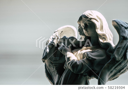 Statue of an angel playing harp in the garden 58219304