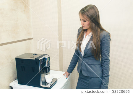Making coffee in the coffee machine. A girl in a 58220695