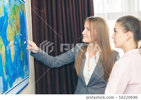 Two business-like young women plot a route on a 58220696