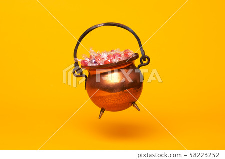 Iron pot with multi-colored sweets on orange background 58223252