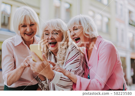 Three old females looking at the phone and laughing Three old females looking at the phone and laughing 58223580