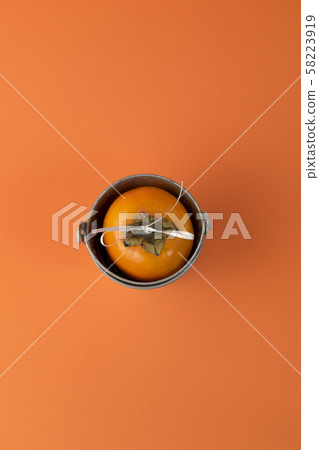 One ripe persimmon in basket on orange background. 58223919