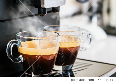 freshly brewed coffee is poured from the coffee machine into glass cups 58224055