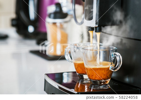 freshly brewed coffee is poured from the coffee machine into glass cups freshly brewed coffee is poured from the coffee machine into glass cups 58224058