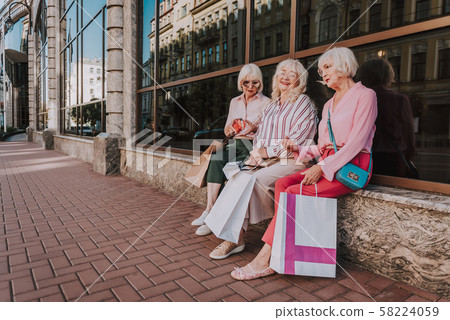 Three stylish female pensioners are sitting near mall Three stylish female pensioners are sitting near mall 58224059