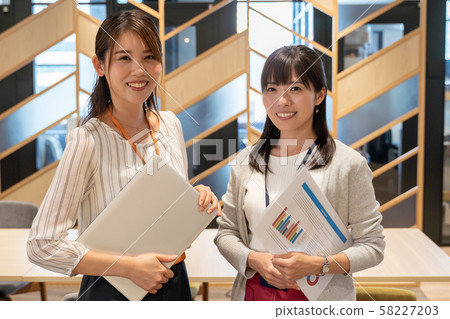 兩名婦女在辦公室與文件和筆記本電腦 58227203