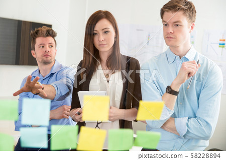 Businesswoman Looking At Strategies On Adhesive Notes By Colleag 58228894