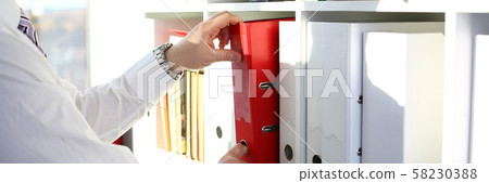 Male arms pick red file folder from office book shelf 58230388