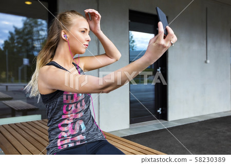 Beautiful Woman In Sportswear Taking Selfie While Sitting On Ben Beautiful Woman In Sportswear Taking Selfie While Sitting On Ben 58230389