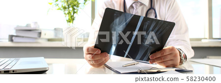 Male doctor hold in arm silver pen and look at xray Male doctor hold in arm silver pen and look at xray 58230400