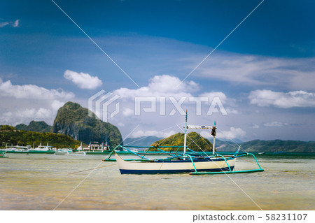 Traditional banca fishermen boat in shallow lagoon on Corong Beach. Nido, Philippines. Blue sky and 58231107