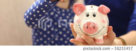 Child little girl arm putting coins into piggybank 58231457