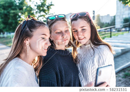3 teenage girls 12-15 years old summer in city look mobile phone, take selfies, read watch video 3 teenage girls 12-15 years old summer in city look mobile phone, take selfies, read watch video 58231531