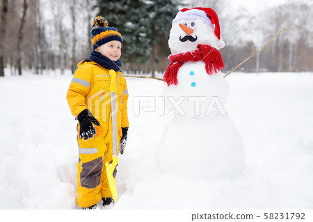 Little boy playing with funny snowman. Active Little boy playing with funny snowman. Active 58231792