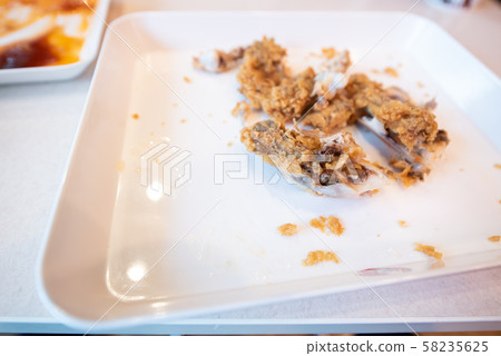 Bones of fried chicken and some scrap on white dish after eating roasted.Food waste, chicken bone waste, scrap chicken bone. Bones of fried chicken and some scrap on white dish after eating roasted.Food waste, chicken bone waste, scrap chicken bone. 58235625