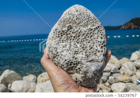 Natural pumice stone in hand on sea background 58239767
