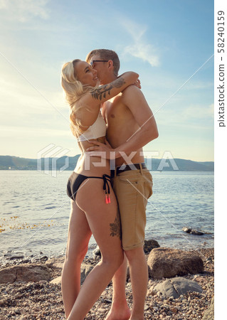 Young Couple Standing On Rock And Holding Each Other At Beach 58240159