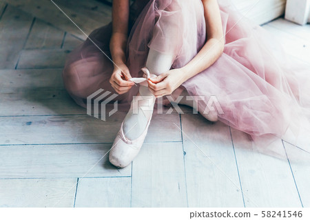 Ballerina hands puts pointe shoes on leg in dance 58241546