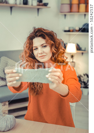 Amazing red - haired girl looking at piece of linen 58242537