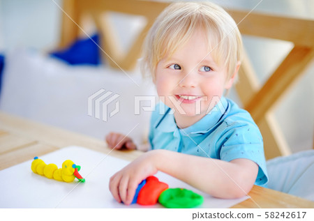 Creative boy playing with colorful modeling clay Creative boy playing with colorful modeling clay 58242617