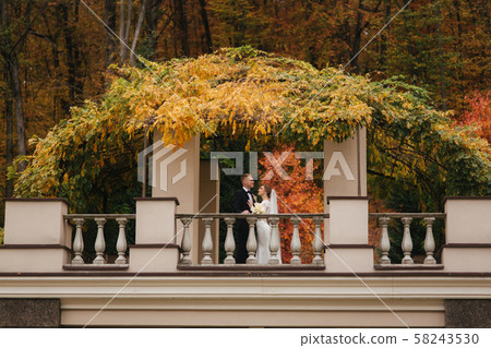 Beautiful wedding couple stand on the balcony. Stylish bride and groom in autumn weather outside 58243530