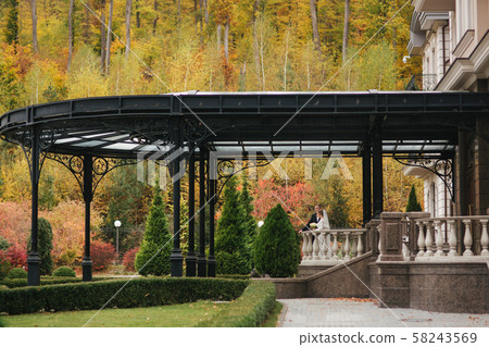 Beautiful wedding couple stand on the balcony. Stylish bride and groom in autumn weather outside Beautiful wedding couple stand on the balcony. Stylish bride and groom in autumn weather outside 58243569