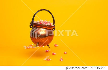 Iron pot with multi-colored sweets on blank orange background. Iron pot with multi-colored sweets on blank orange background. 58245353