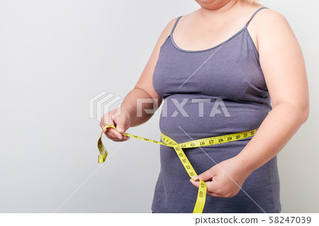 Overweight woman measuring her fat belly 58247039