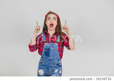 Pretty girl with widely opened mouth, pointing her fingers up. 58248716