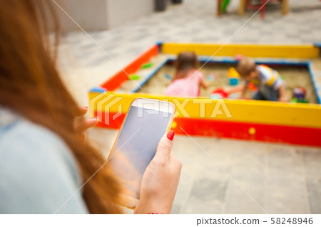 Mother sitting and looking at the screen of smartphone 58248946