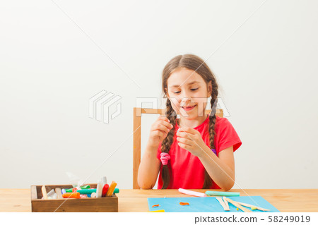 Girl play with colorful modeling clay at tha table Girl play with colorful modeling clay at tha table 58249019