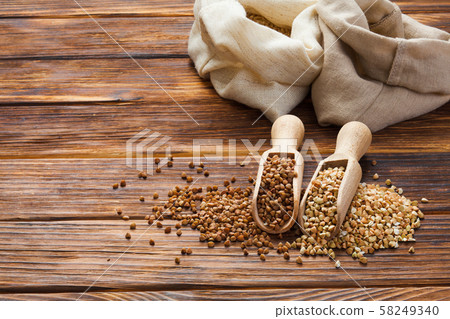 Green and fried buckwheat grains in the wooden scoops 58249340