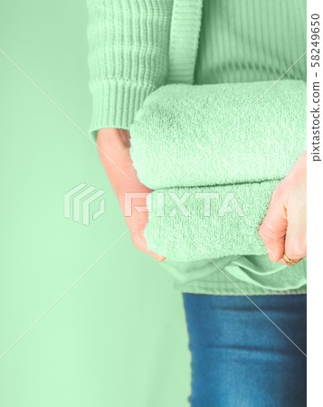 Woman holding clean green mint folded towels 58249650