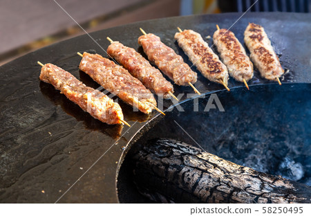 Grilled appetizing kebab cooking on wooden skewers 58250495