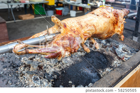Cooking lamb carcass on a spit over hot charcoals 58250505
