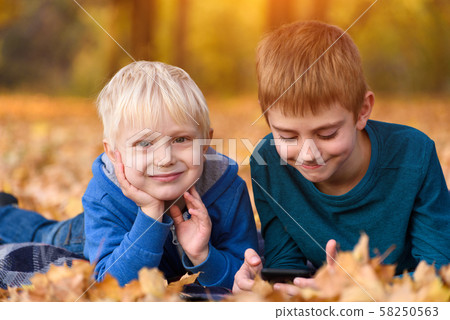 Two little brothers lying in yellow autumn leaves. Two little brothers lying in yellow autumn leaves. 58250563