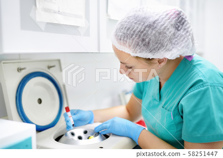 Lab woman puts in a centrifuge tube of blood. Lab woman puts in a centrifuge tube of blood. 58251447