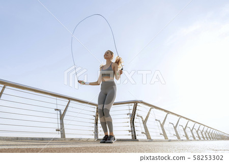 Happy sportive lady jumping rope on bridge Happy sportive lady jumping rope on bridge 58253302