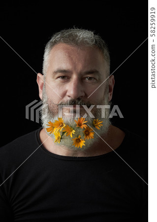 Portrait of a smiling brutal man with a gray beard decorated with yellow flowers on a black Portrait of a smiling brutal man with a gray beard decorated with yellow flowers on a black 58259919