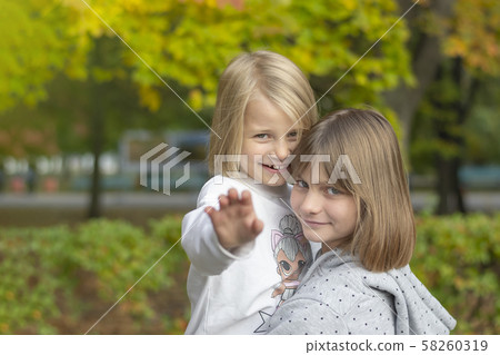 Two happy girls are playing in the autumn park. 58260319