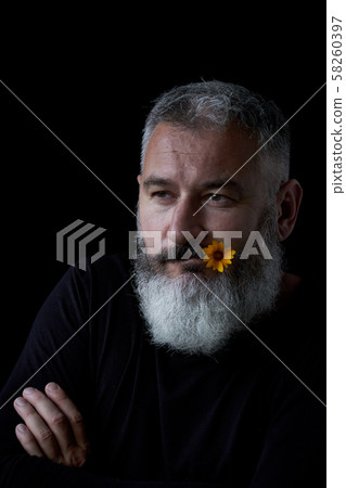 Portrait of a brutal gray haired man with a beard with a sly expression on his face and a yellow 58260397